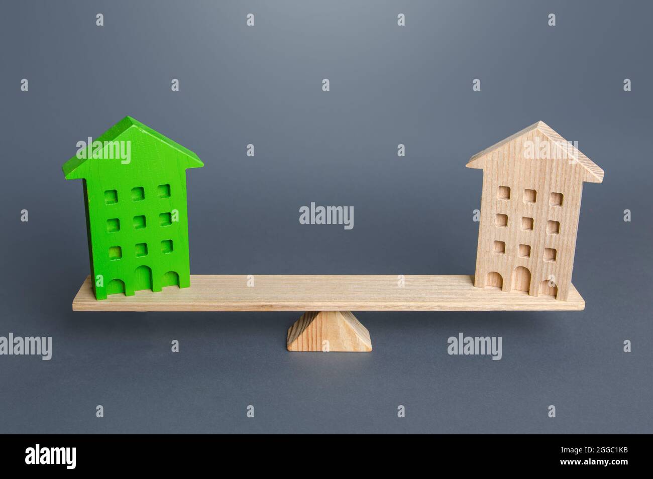 Des maisons vertes et ordinaires sont sur la balance. Comparaison des logements écologiques avec les logements conventionnels. Avantages et inconvénients de l'efficacité énergétique Banque D'Images