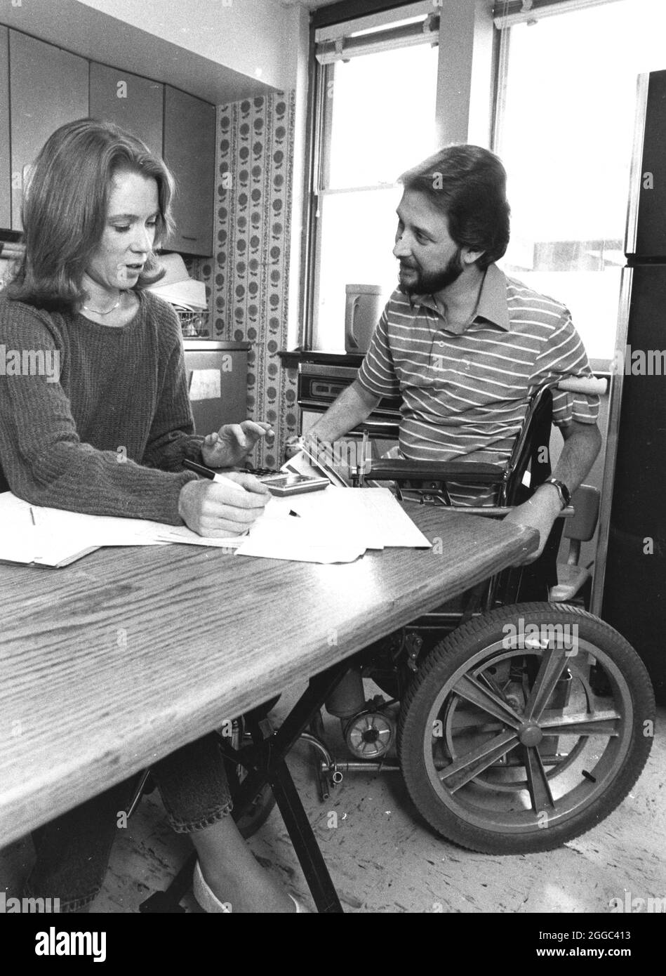 Austin Texas USA, 1993 : homme handicapé en fauteuil roulant et sa femme travaillent sur le budget du ménage et équilibrent le compte courant sur leur table de cuisine. Bob et Janis Daemmrich ©Bob Daemmrich Banque D'Images