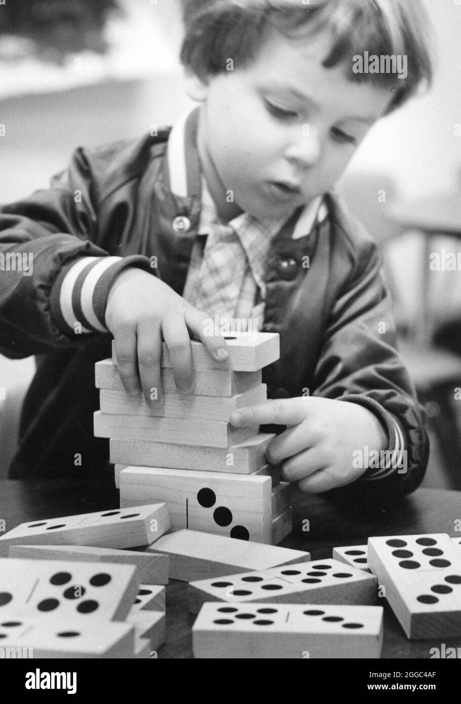 Austin Texas USA, circa 1989 : étudiant à l'école maternelle empile de grands dominos en bois au centre d'activité. ©Bob Daemmrich Banque D'Images