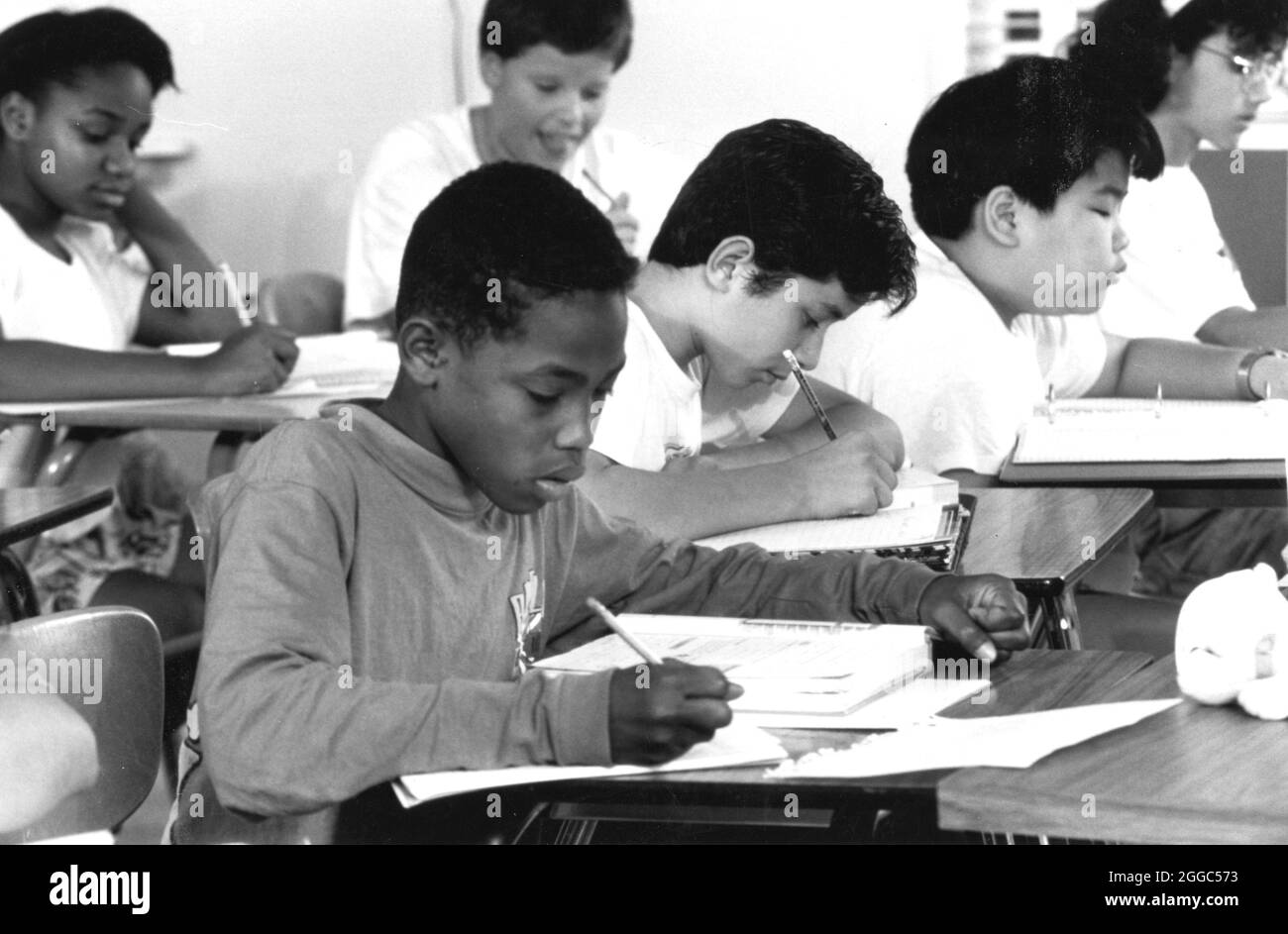 Austin Texas USA, circa 1992 : groupe multiculturel d'élèves de septième année utilisent des crayons et du papier pour écrire pendant les cours d'anglais du collège. (original en couleur). ©Bob Daemmrich Banque D'Images