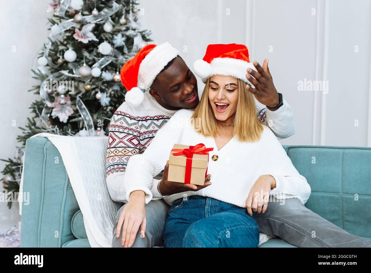 Une femme est surprise par le don que son mari lui a donné. Couple partageant cadeau de Noël. Portrait d'un couple charmant en période de noël. Banque D'Images