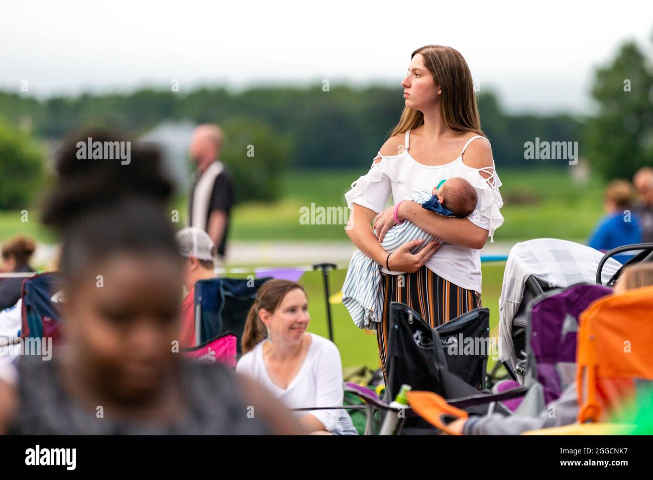 Une jeune mère berce son bébé au milieu de la foule lors d'un concert en plein air en Angola, dans l'Indiana, aux États-Unis. Banque D'Images