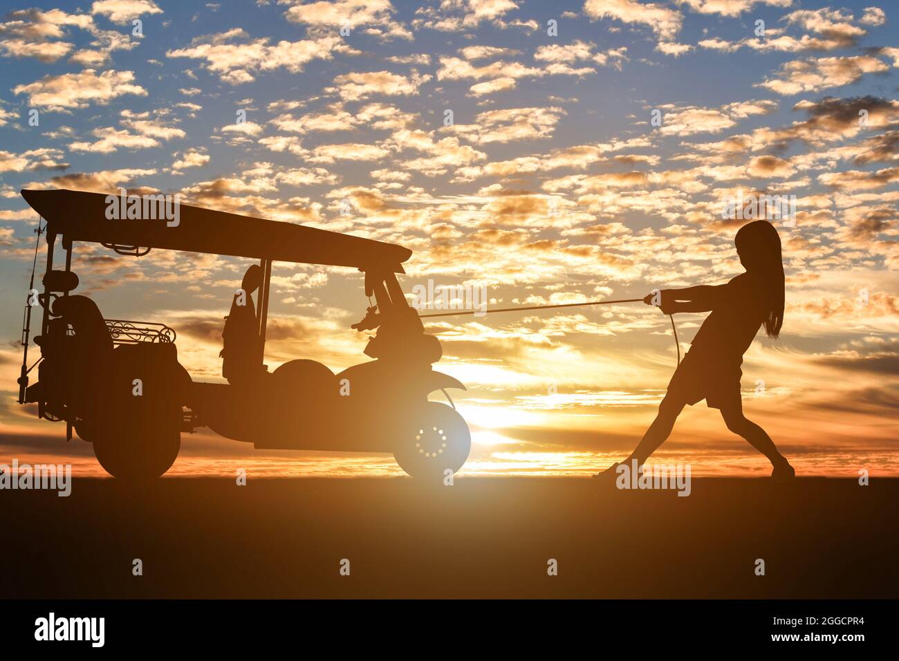 Silhouette de tricycle à moteur tirant femelle sur fond de coucher de soleil. Banque D'Images