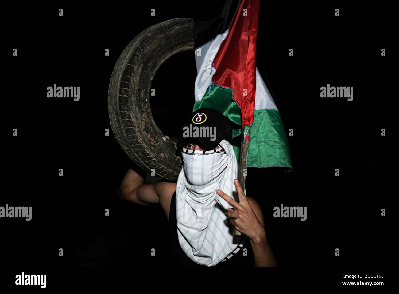 Gaza, Palestine. 30 août 2021. Un manifestant palestinien portant un drapeau palestinien porte un pneu à brûler lors des affrontements avec l'armée israélienne le long de la frontière entre la bande de Gaza et Israël, à l'est de Khan Yunis. Protestation contre la poursuite du siège imposé dans la bande de Gaza. (Photo de Yousef Masoud/SOPA Images/Sipa USA) crédit: SIPA USA/Alay Live News Banque D'Images