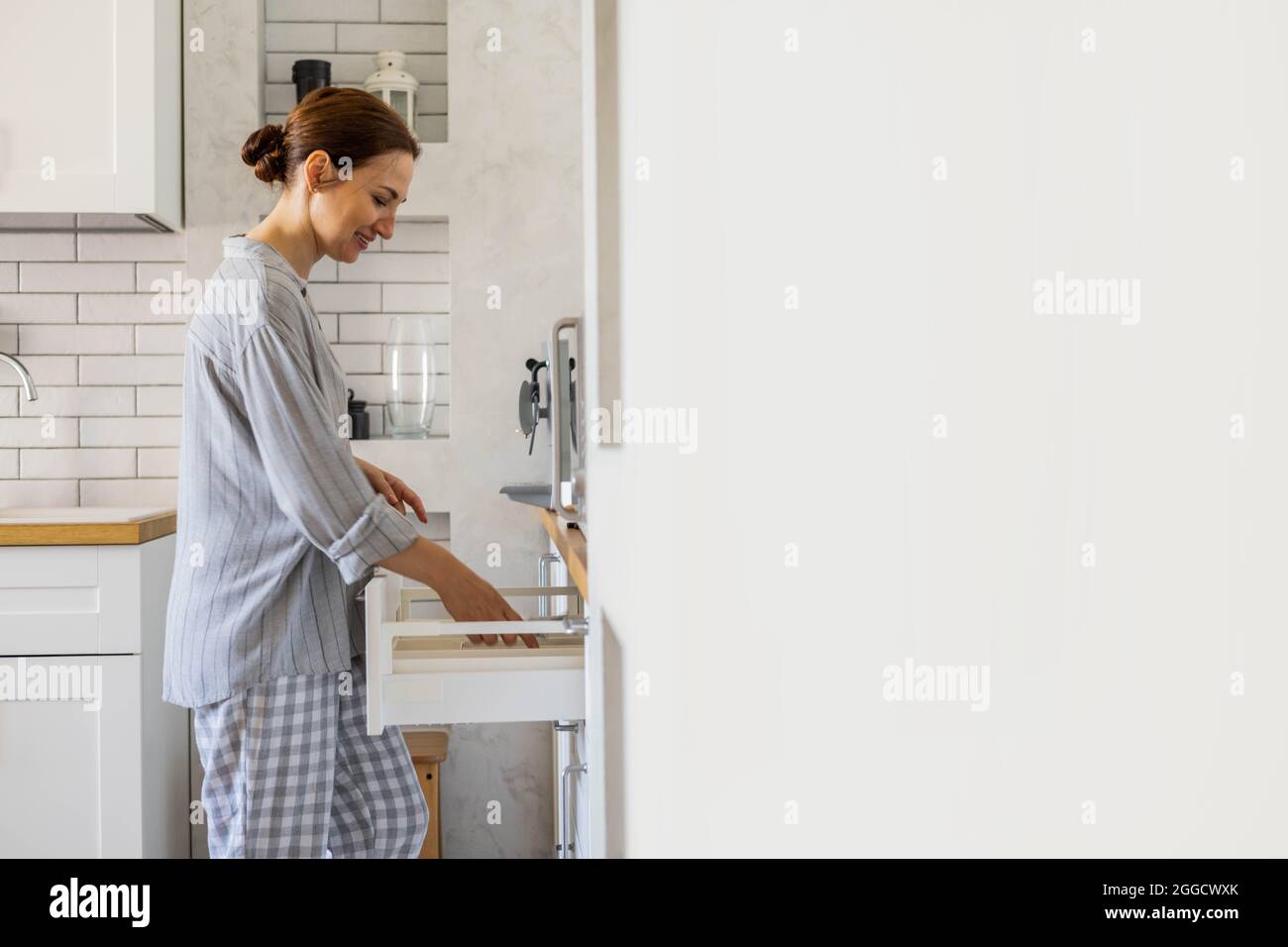 une femme de ménage moderne se lapidant dans la cuisine lors du nettoyage général ou de la mise en armoire Banque D'Images