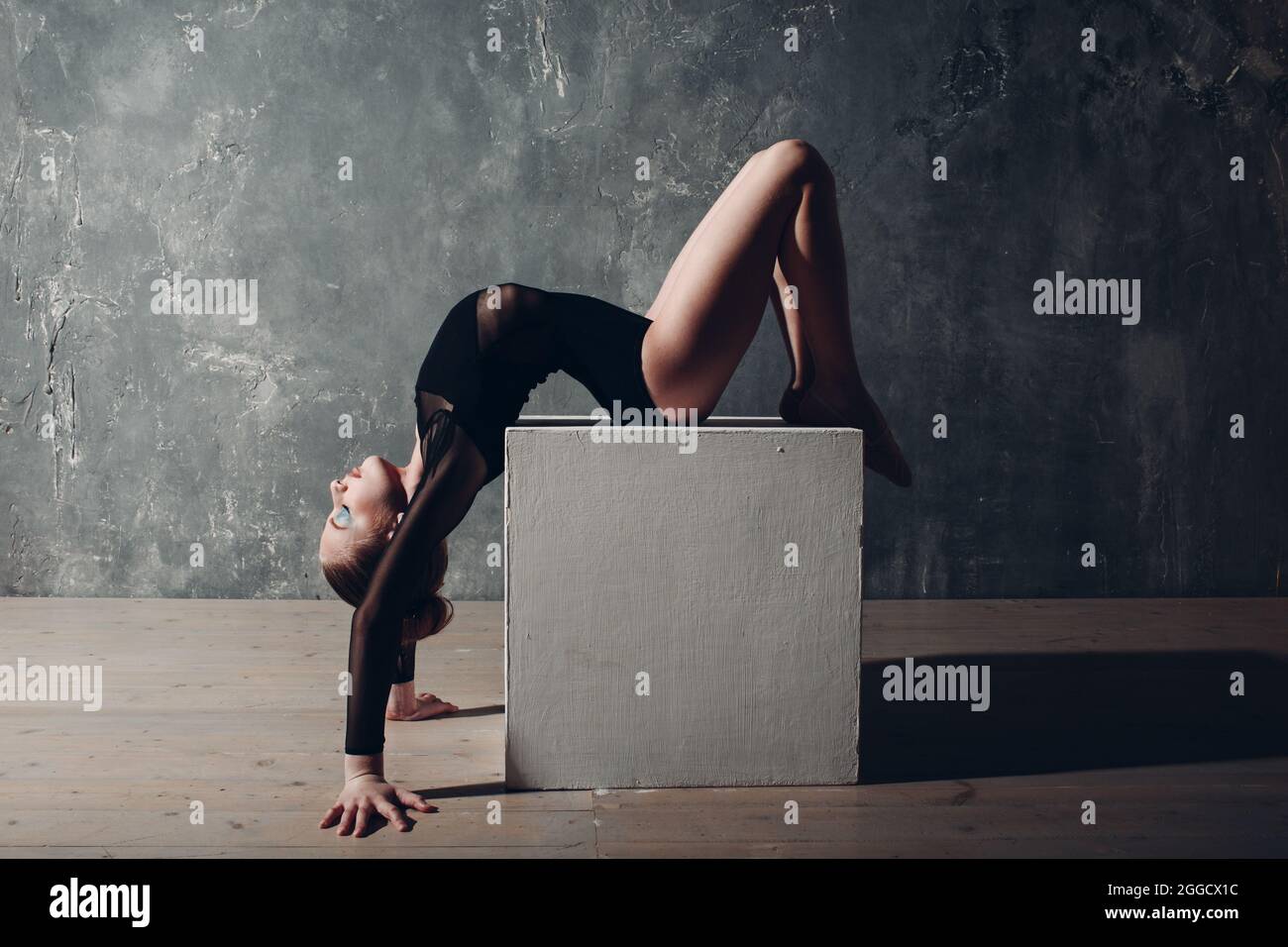 Jeune fille professionnelle gymnaste femme danse gymnastique rythmique avec cube blanc au studio. Banque D'Images