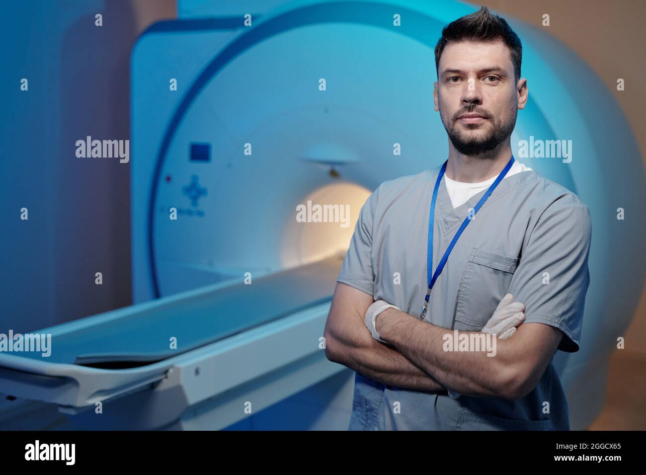 Jeune professionnel de la tomographie confiant croisant les bras par poitrine contre la machine ct Banque D'Images