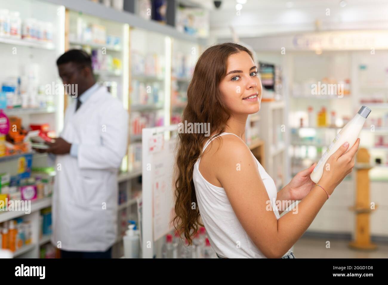 Adolescente choisissant des produits de soins capillaires en pharmacie Banque D'Images