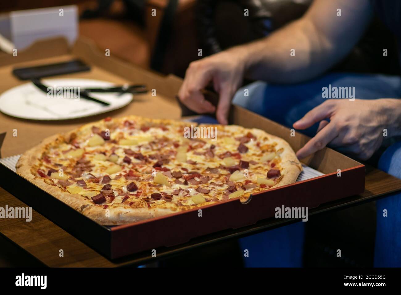 Personne tenant avec les mains livraison pizza sur la table en bois Banque D'Images