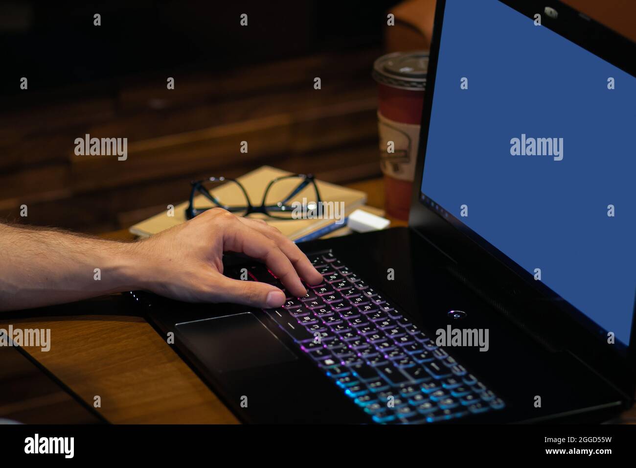 Adulte jeune personne dactylographiant et travaillant sur un ordinateur portable sur la table en bois Banque D'Images