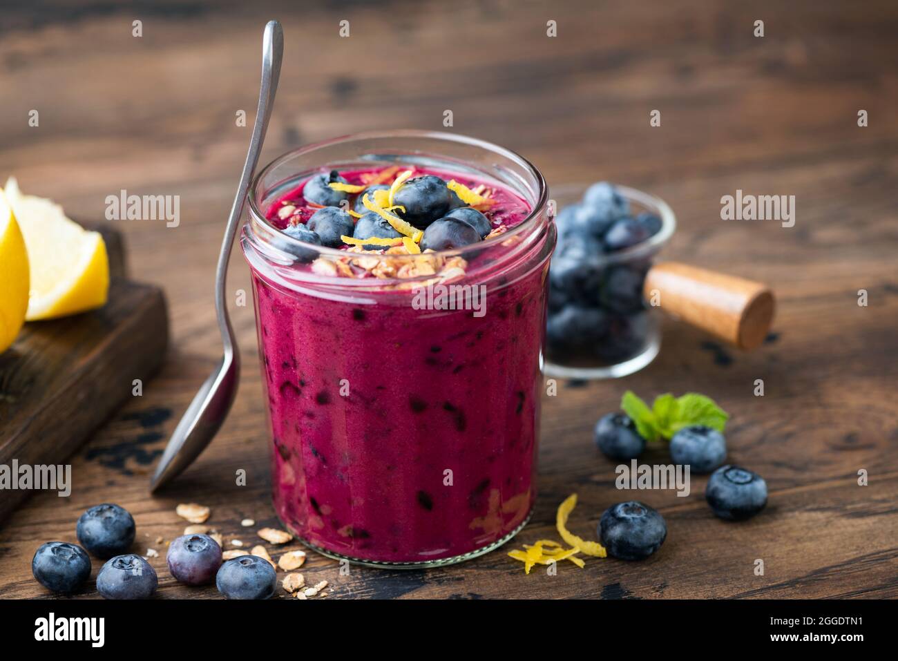 Smoothie aux myrtilles épaisses dans un pot en verre sur une table en bois. Nourriture végétalienne Banque D'Images