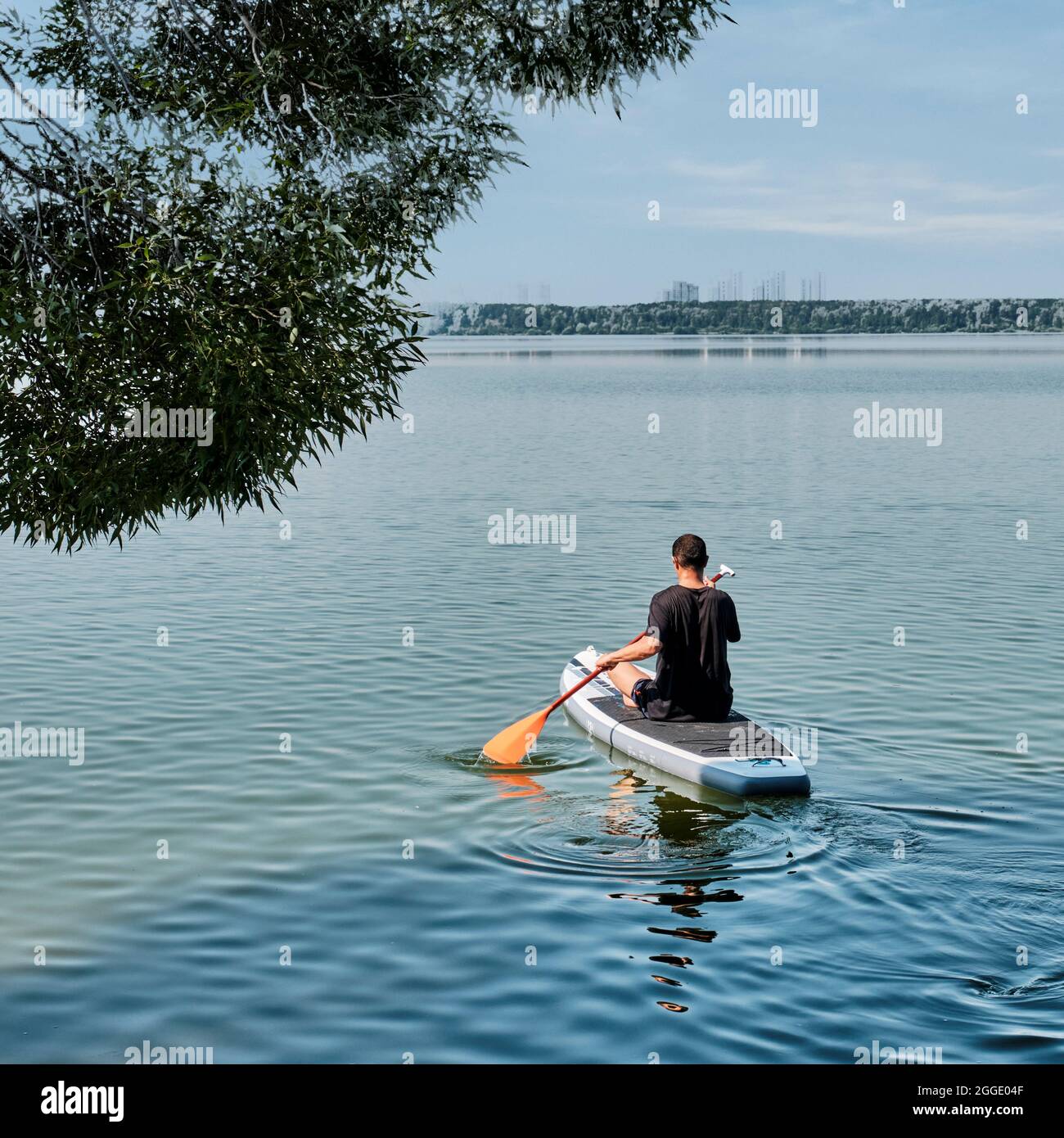Homme asiatique plus âgé à bord supérieur sur un lac calme. Banque D'Images