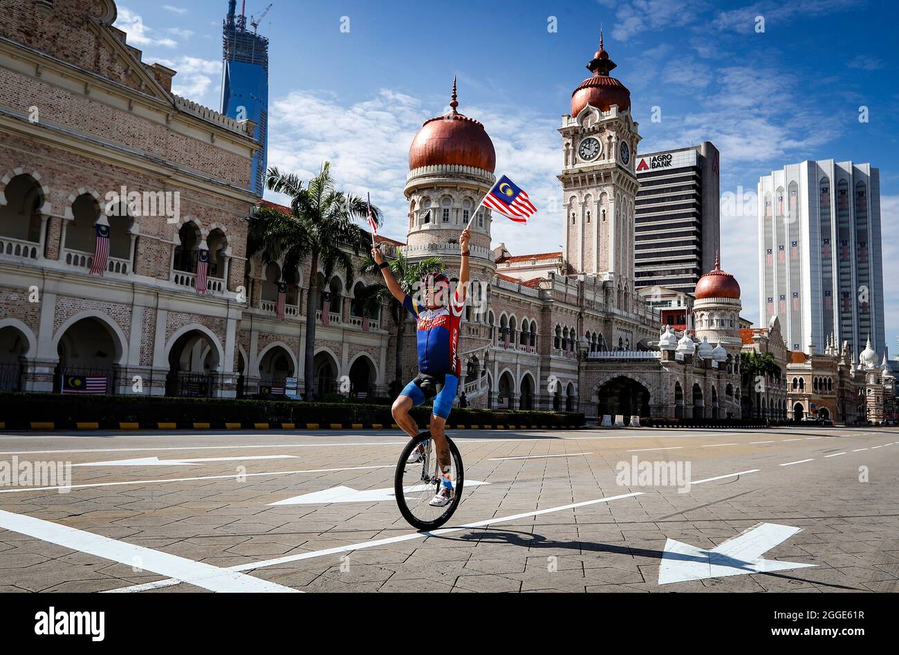 Kuala Lumpur, Malaisie. 31 août 2021. Un homme passe un monocycle tout en tenant des drapeaux malaisiens lors des célébrations de la 64e Journée nationale à Kuala Lumpur.la Malaisie célébrant chaque année son 64ème jour de l'indépendance le 31 août, elle commémore la Déclaration d'indépendance de Malaisie du 31 août 1957. Crédit : SOPA Images Limited/Alamy Live News Banque D'Images