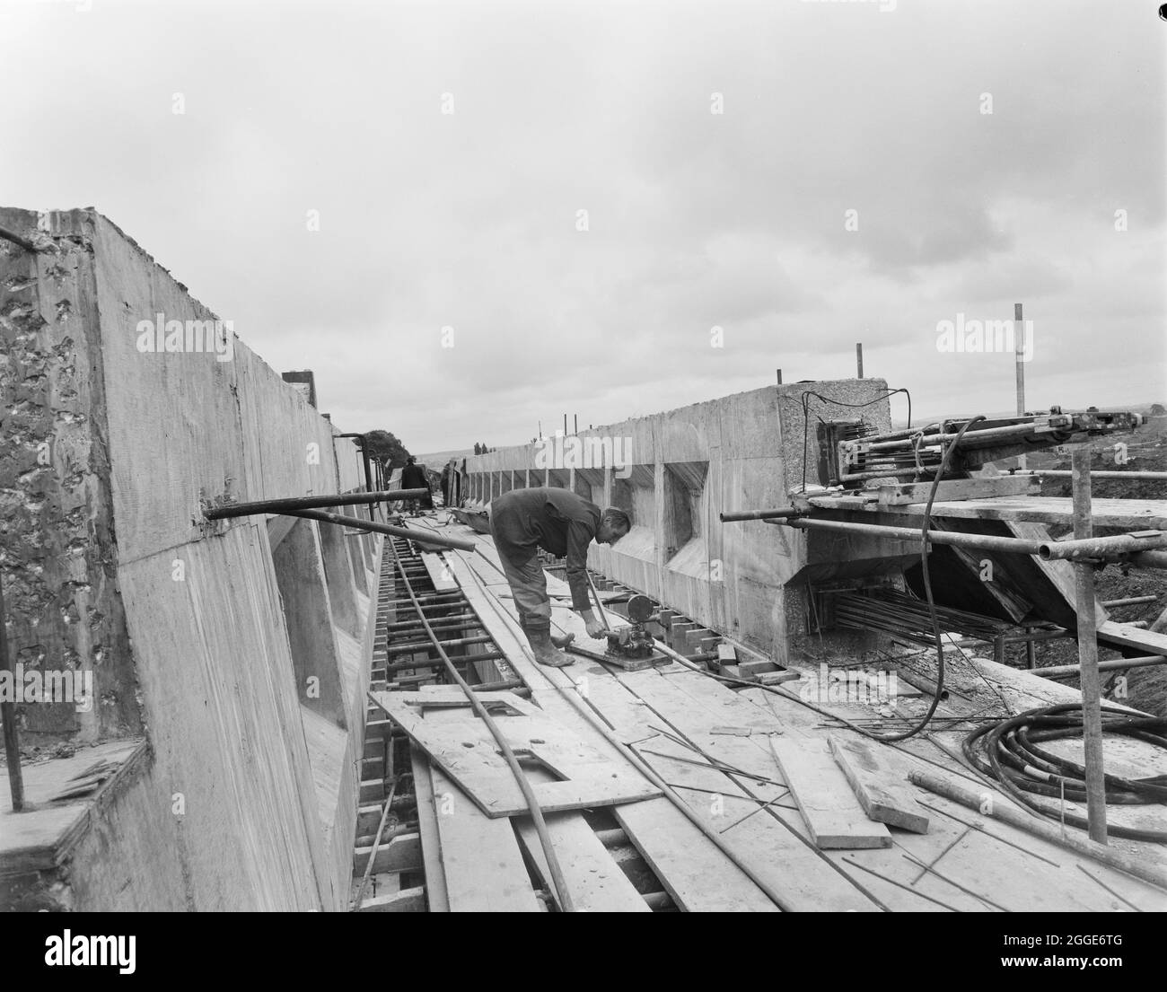 Vue de la construction de la structure 306 (pont Barn Bank Lane) sur l'autoroute Birmingham-Preston (M6), montrant un travailleur effectuant la contrainte du béton précontraint. Ce pont routier, situé au SJ9211419999, a ouvert ses portes en mars 1962. Banque D'Images