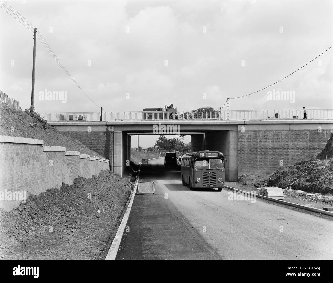 Vue sur la construction de l'autoroute Birmingham-Preston (M6), montrant un bus Midland Red (Service 98 à Coppenhal) en passant sous le pont Burton Manor Road, avec travaux de construction sur l'autoroute ci-dessus. L'emplacement de ce pont routier est au numéro de grille SJ9155420677. Banque D'Images