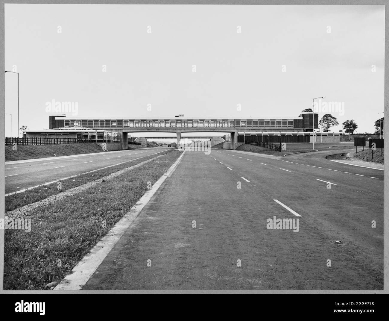 Vue vers le nord en direction de la structure 347A, dans la zone de service Keele de l'autoroute Birmingham-Preston (M6), montrant un panneau d'entrepreneur Laing sur la passerelle couverte au-dessus de l'autoroute. Cette image a été cataloguée dans le cadre du projet Breaking New Ground en partenariat avec la John Laing Charitable Trust en 2019-20. Banque D'Images