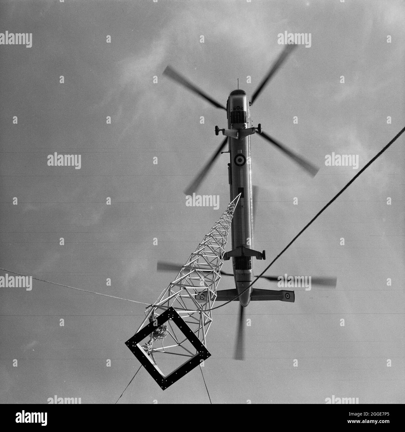 Vue sur un hélicoptère du Belvédère de la RAF en cours d'abaissement de la flèche de bronze de 80 pieds sur le toit de la cathédrale de Coventry. La photographie a été prise lors de l'opération Rich Man, projet conjoint impliquant le personnel de la Royal Air Force et le personnel de Laing. Cela impliquait un hélicoptère de la RAF Belvedere qui se leva pour placer la flèche de bronze de 80 pieds sur la nouvelle cathédrale. La partie de l'opération d'abaissement de la croix de 1/2 tonnes qui se trouve au-dessus de la flèche a dû être reportée en raison de conditions venteuses. Banque D'Images