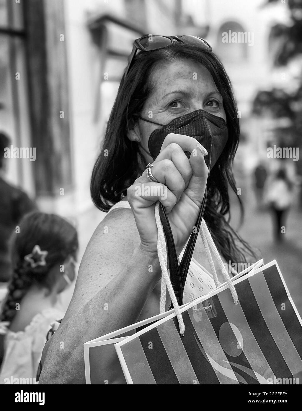Prise de vue verticale en niveaux de gris d'une femme d'âge moyen du Caucase portant un masque et tenant un sac Banque D'Images