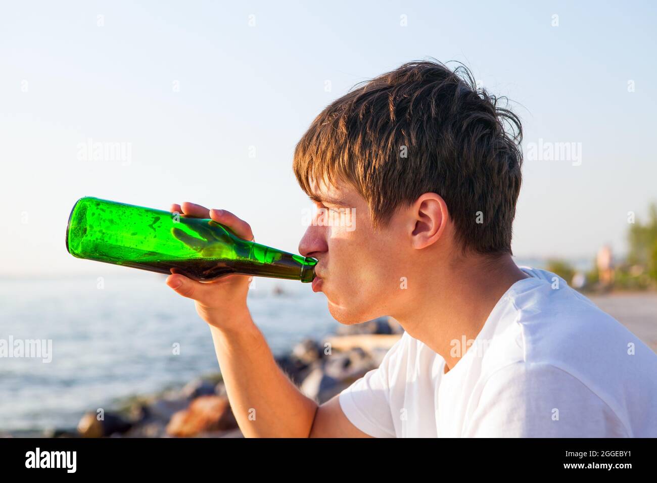Un jeune homme boit une bière sur le fond marin Banque D'Images