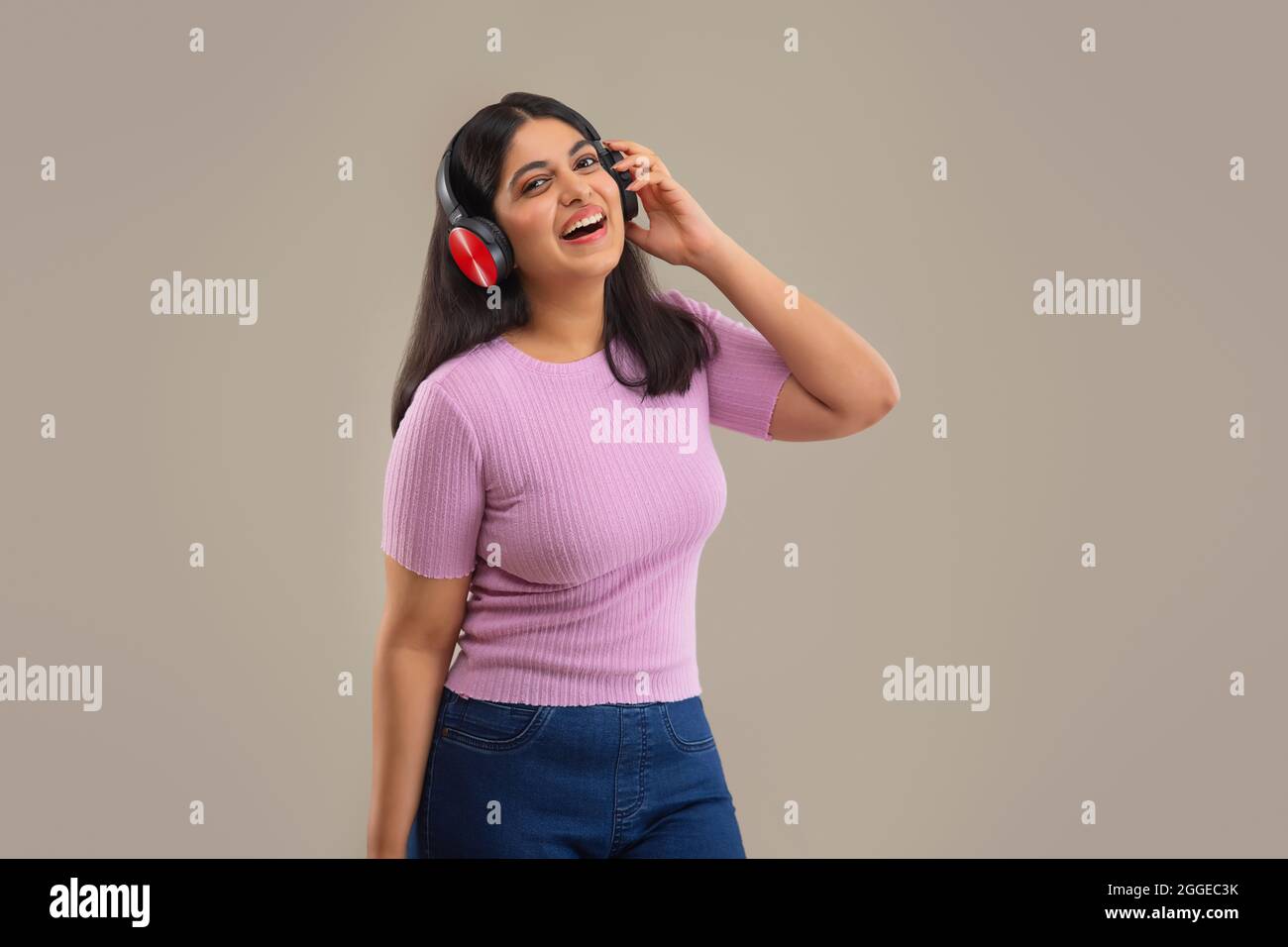 UNE JEUNE FEMME JOYEUSE QUI ÉCOUTE DE LA MUSIQUE DEVANT L'APPAREIL PHOTO Banque D'Images