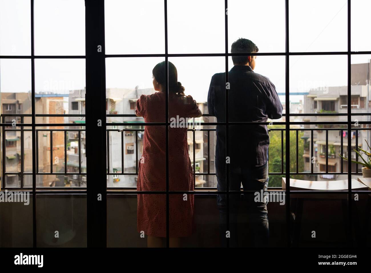 Jeune couple debout dans le balcon de leur appartement donnant à l'extérieur. Banque D'Images