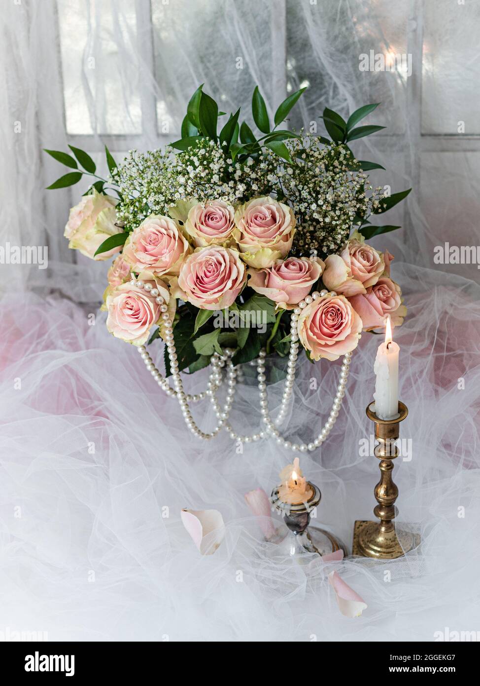 Shabby chic mariage encore vie arrangement avec des fleurs roses, bougie et perles. Banque D'Images