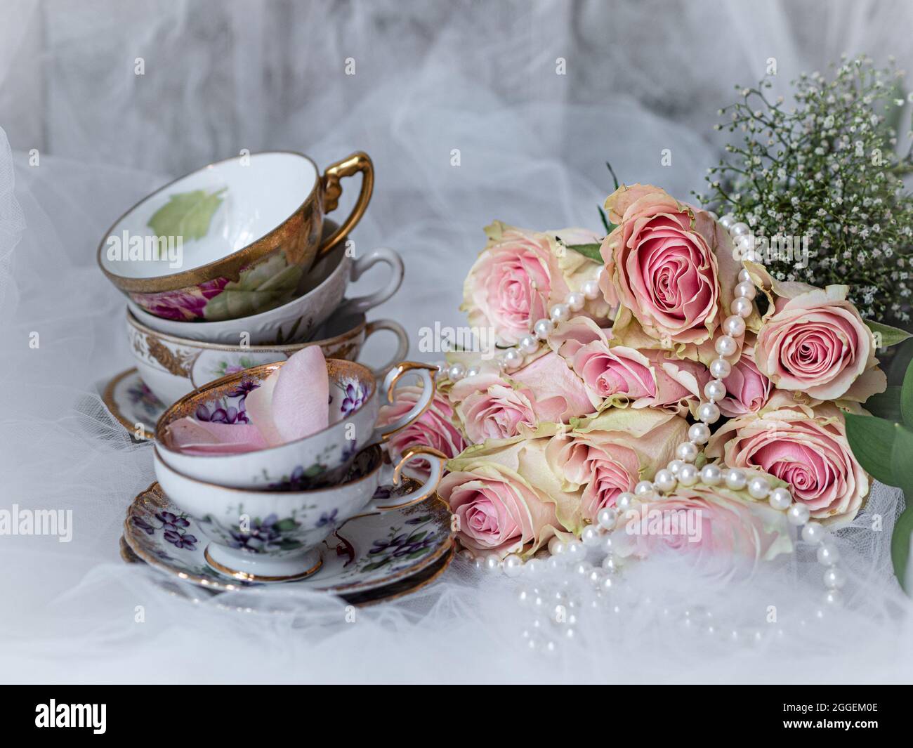 Shabby chic mariage encore vie arrangement avec des fleurs roses, des tasses de thé vintage et des perles. Banque D'Images