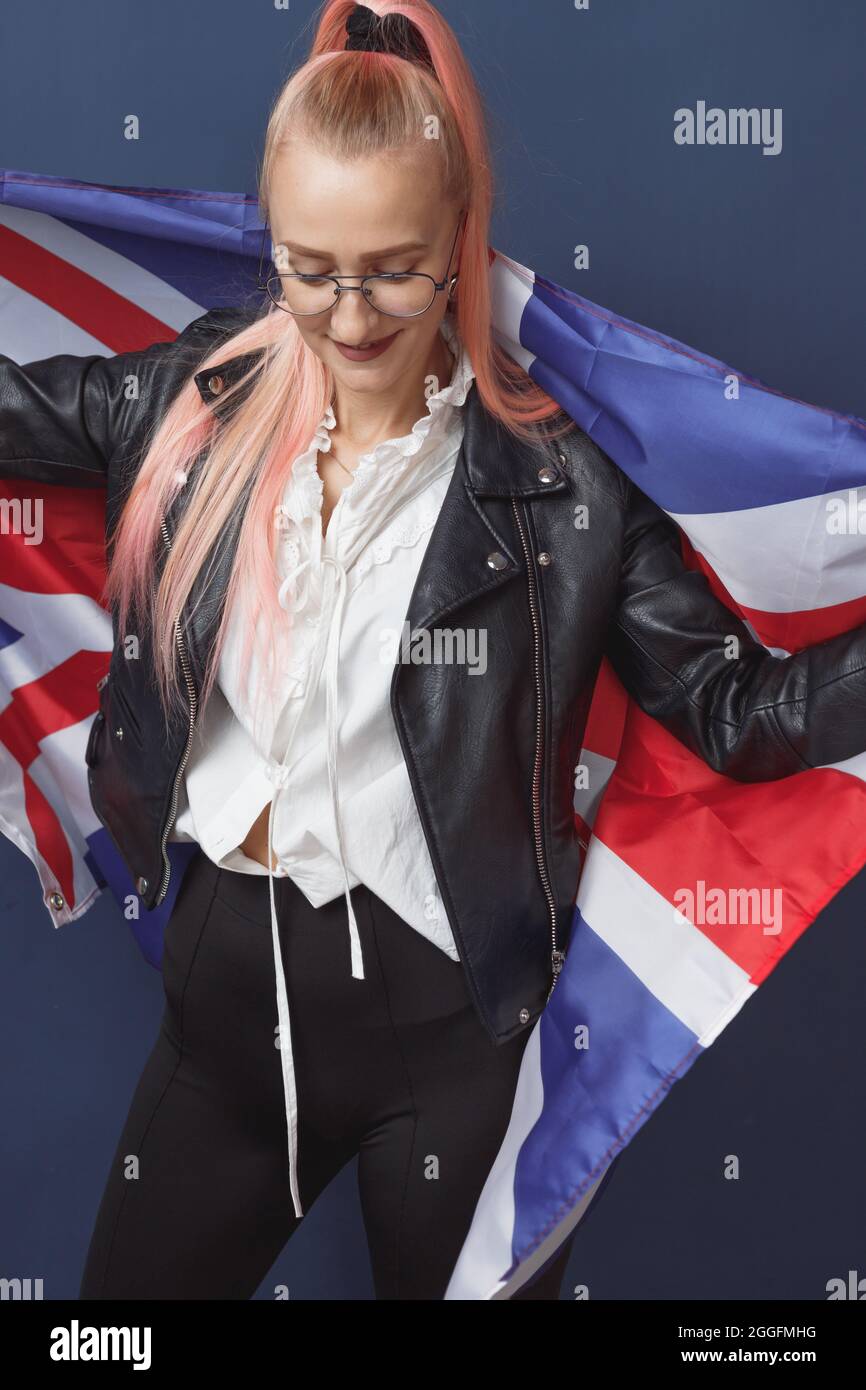 Jeune femme expatrié à lunettes avec le drapeau de la Grande-bretagne. Prise de vue en studio. Enseignant de hippster anglais. Fashionly habit la femme avec des poils roses en noir Banque D'Images