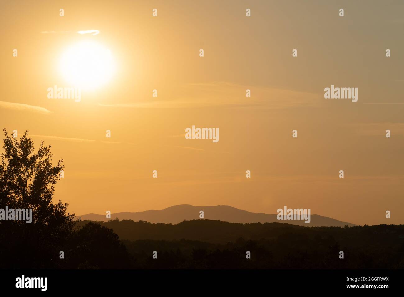 Paysage avec silhouettes de couches de collines pendant la soirée avec le soleil dans le ciel Banque D'Images