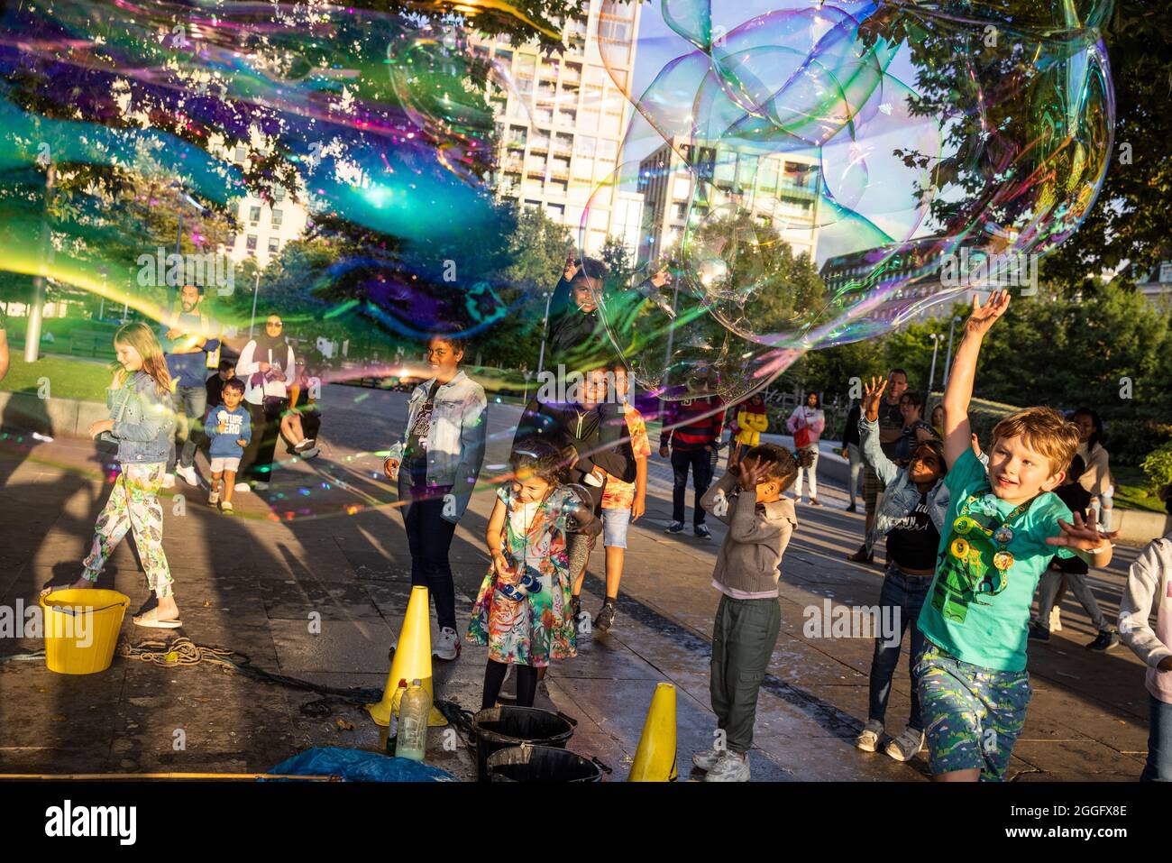 Les familles apprécient les divertissements de la rue le long de la Southbank à Londres tandis qu'un interprète souffle de grandes bulles à travers le pavé, Angleterre, Royaume-Uni. Banque D'Images