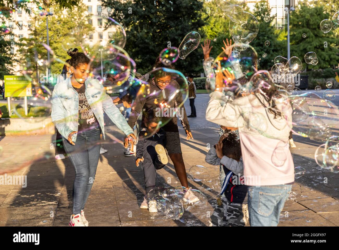 Les familles apprécient les divertissements de la rue le long de la Southbank à Londres tandis qu'un interprète souffle de grandes bulles à travers le pavé, Angleterre, Royaume-Uni. Banque D'Images