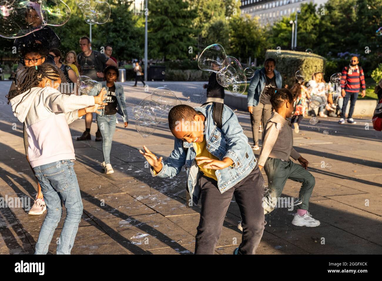 Les familles apprécient les divertissements de la rue le long de la Southbank à Londres tandis qu'un interprète souffle de grandes bulles à travers le pavé, Angleterre, Royaume-Uni. Banque D'Images