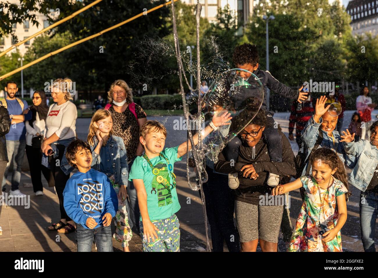 Les familles apprécient les divertissements de la rue le long de la Southbank à Londres tandis qu'un interprète souffle de grandes bulles à travers le pavé, Angleterre, Royaume-Uni. Banque D'Images