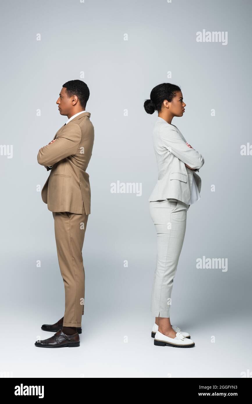 vue de côté des hommes d'affaires afro-américains debout séparément avec des armes croisées sur le concept gris d'égalité des sexes Banque D'Images