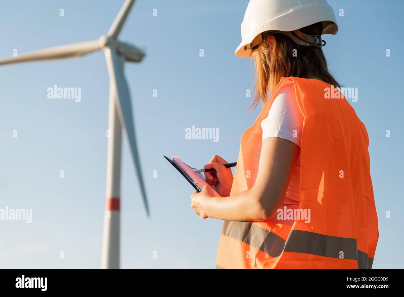 L'ingénieur de maintenance féminin contrôle le travail des éoliennes et des éoliennes. Technologie des énergies renouvelables. Production d'électricité verte. Banque D'Images