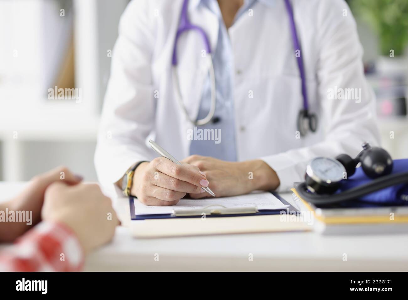 Médecin assis à la table et préparant des dossiers médicaux avec stylo à bille fermé Banque D'Images