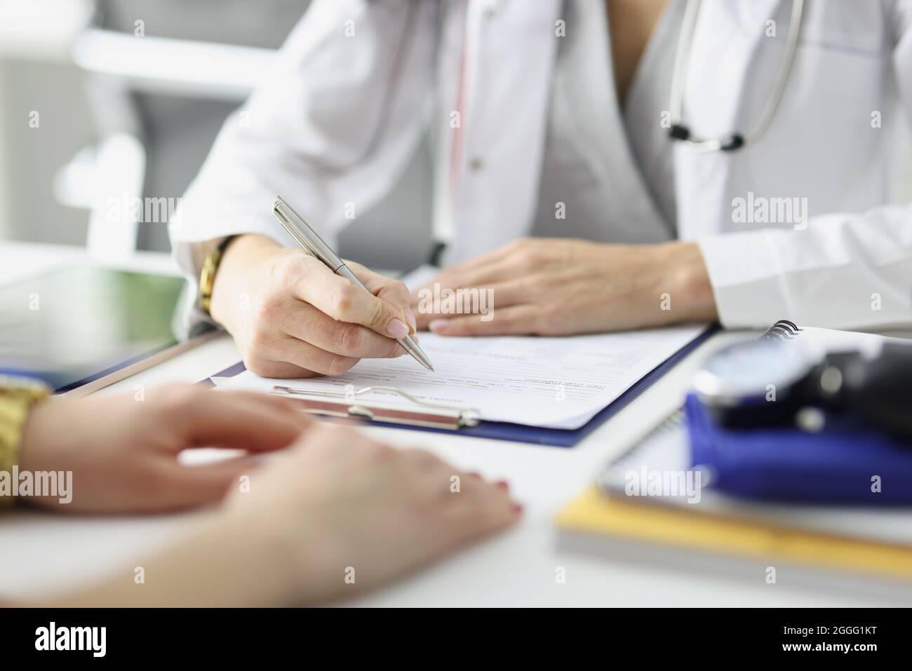 Le médecin écrit des informations dans des documents devant le patient à la fermeture de la clinique Banque D'Images