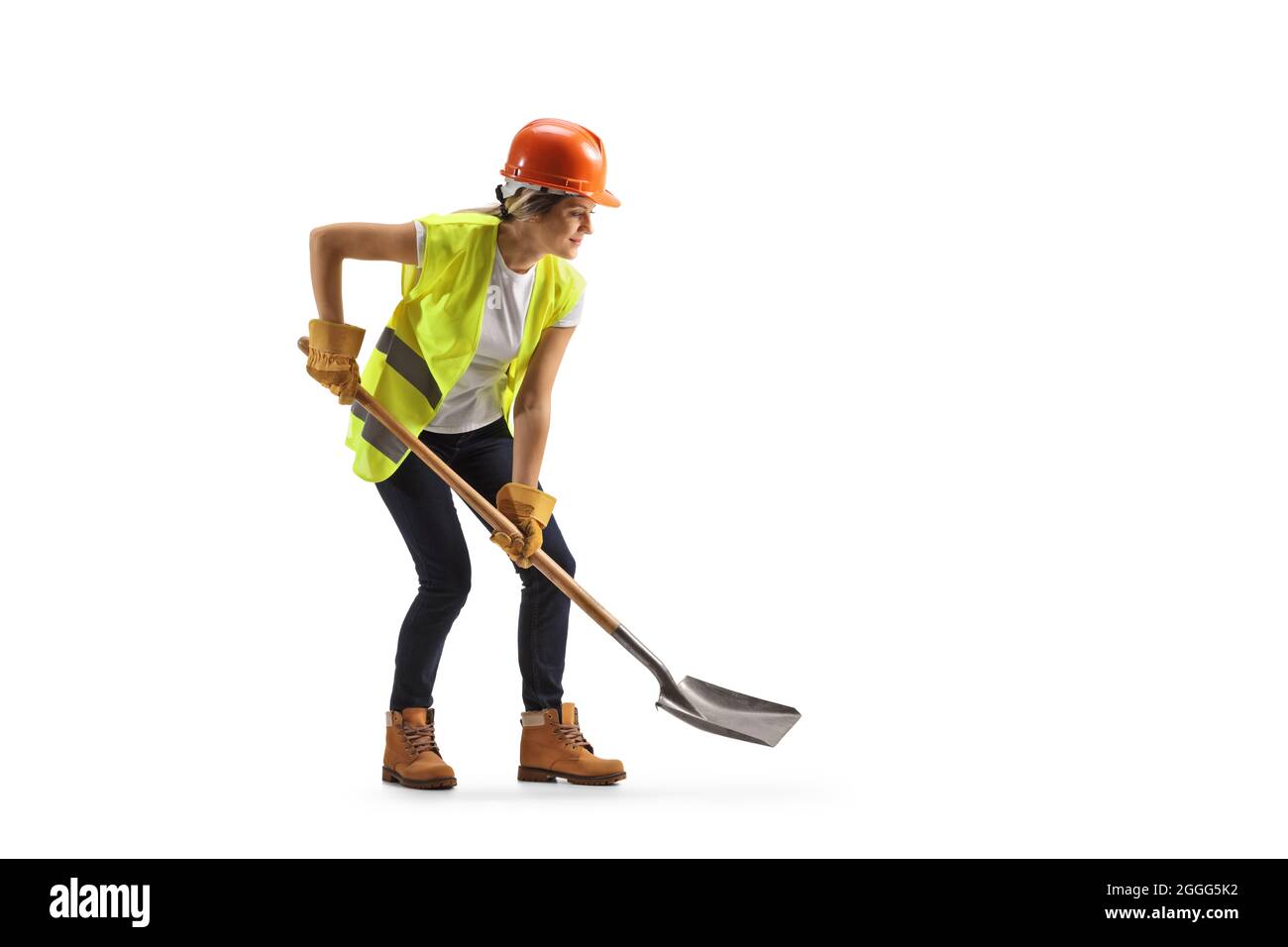 Femme travaillant avec un casque et une ceinture à outils, creusant avec une pelle isolée sur fond blanc Banque D'Images