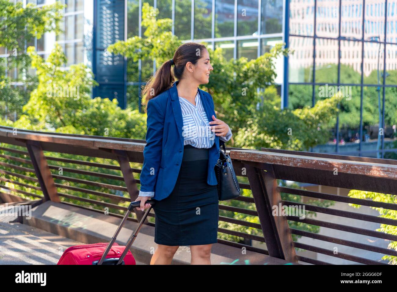 Femme d'affaires caucasienne de taille moyenne avec valise dans la ville Banque D'Images