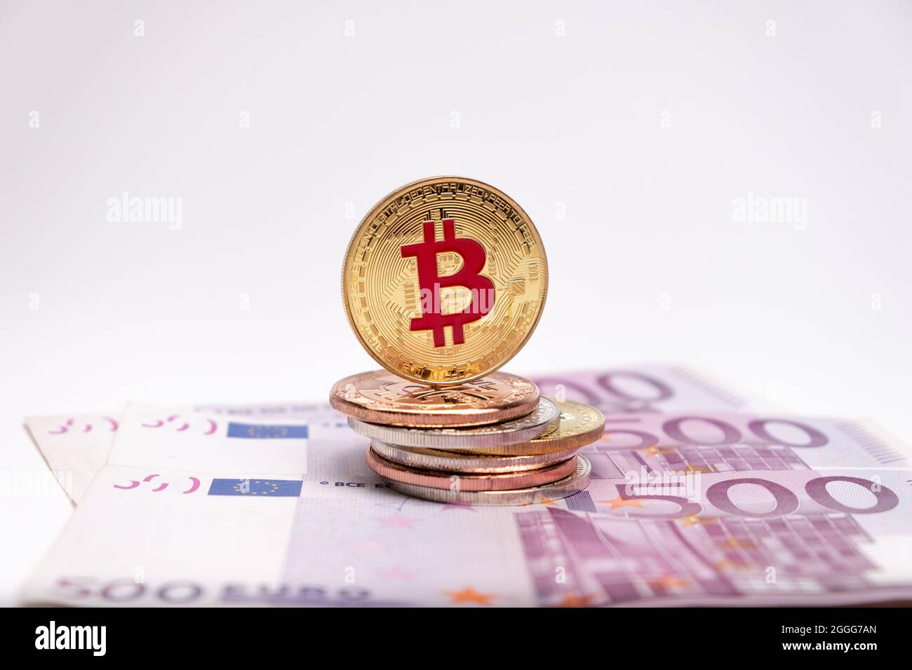 Pièce de monnaie en bitcoin dorée entrée avec le symbole du logo en rouge sur les billets de banque de 500 euros. Le bitcoin en argent se trouve sur cinq cents billets en euros. Banque D'Images