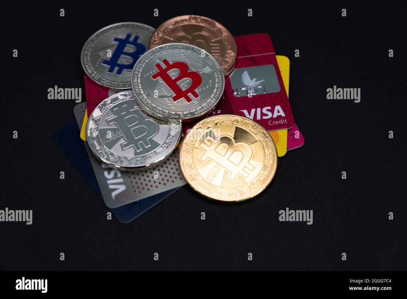 Plusieurs pièces de monnaie en Bitcoin brillantes, avec CARTES DE débit et de crédit VISA sur un fond sombre. Monnaie virtuelle électronique BTC. Banque D'Images