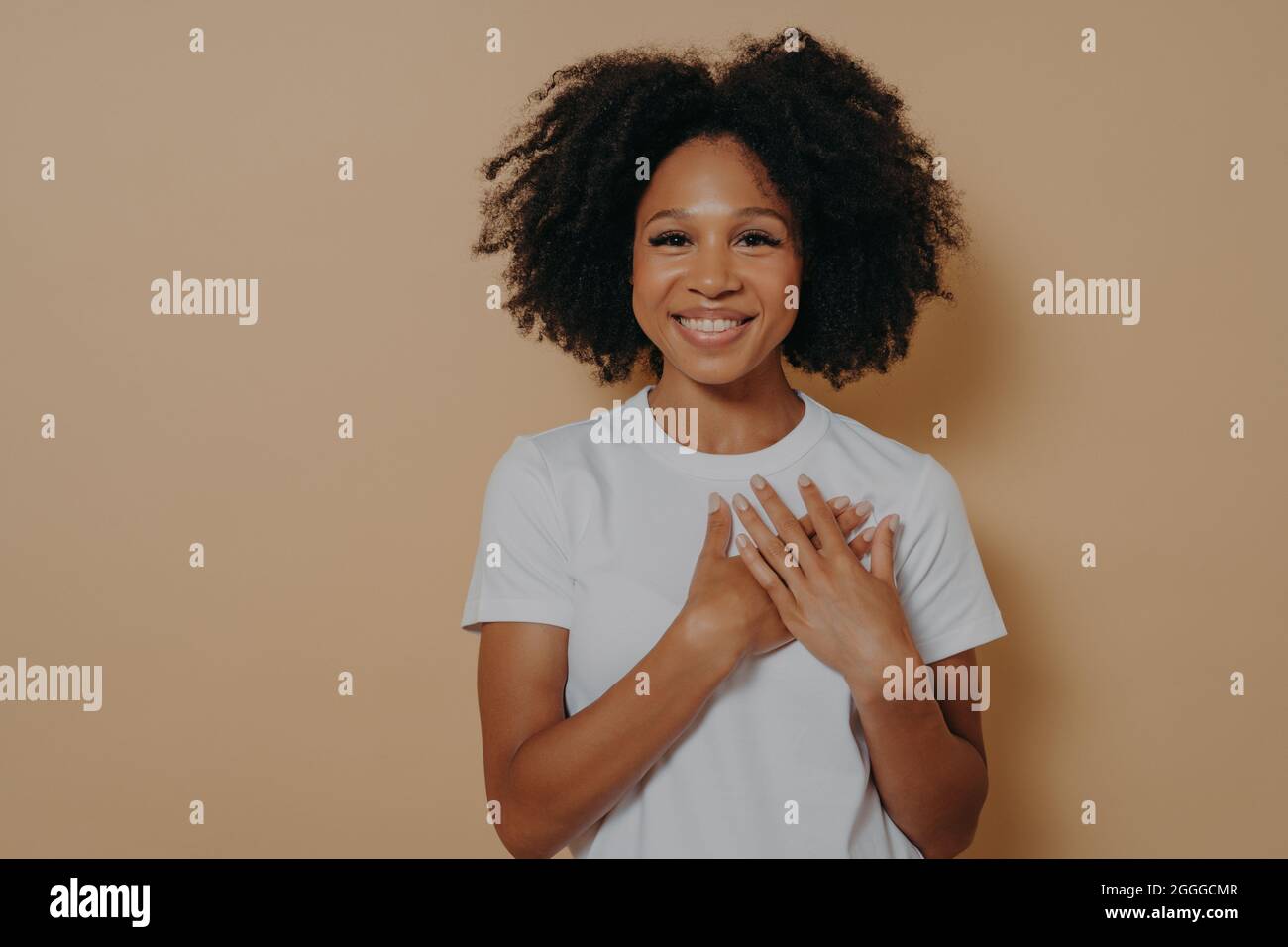 Une jeune femme africaine reconnaissante isolée sur fond de studio jaune montrant de l'appréciation et de l'amour Banque D'Images