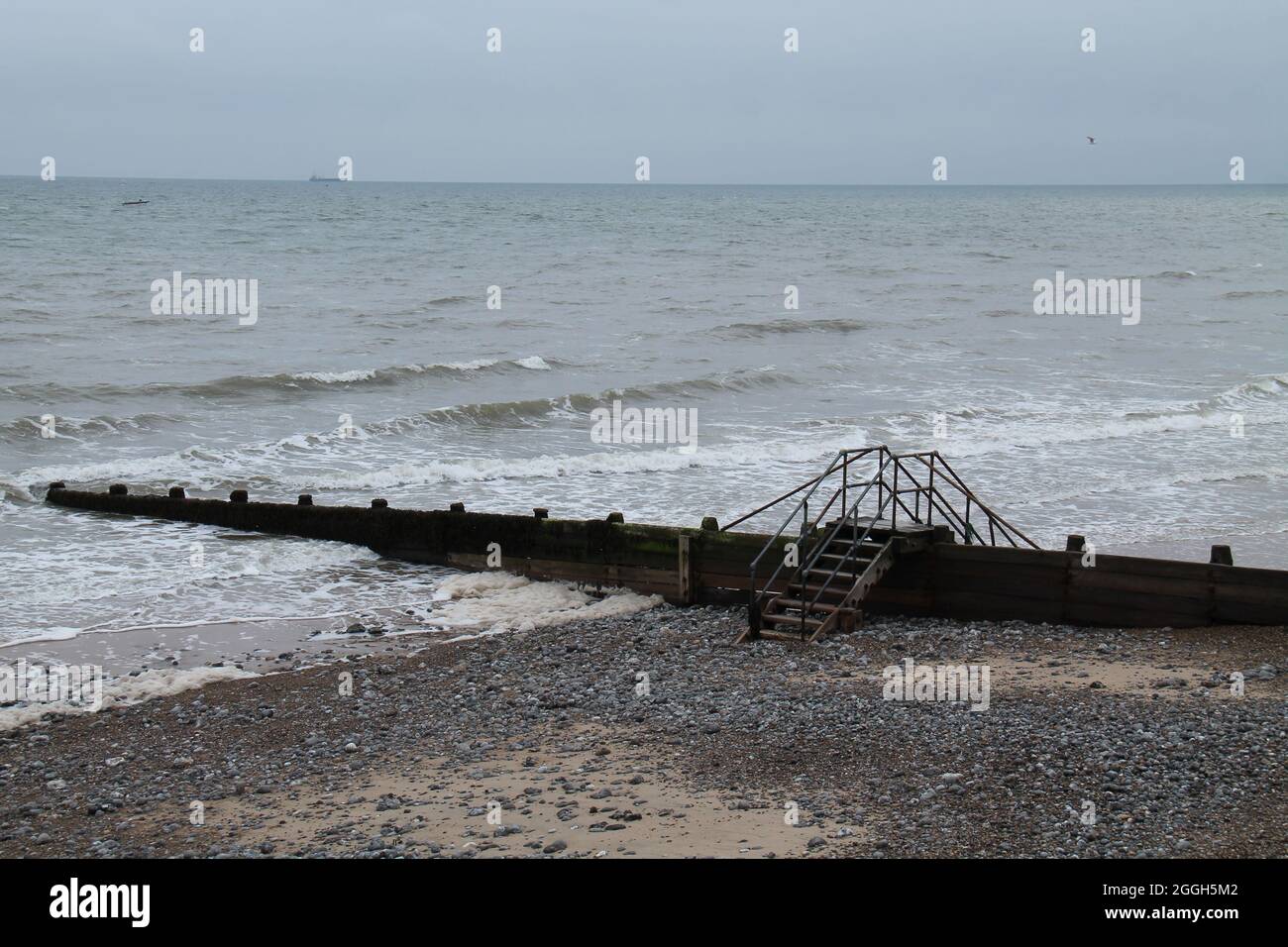 Les marches sur une protection de plage côtière Groyne. Banque D'Images