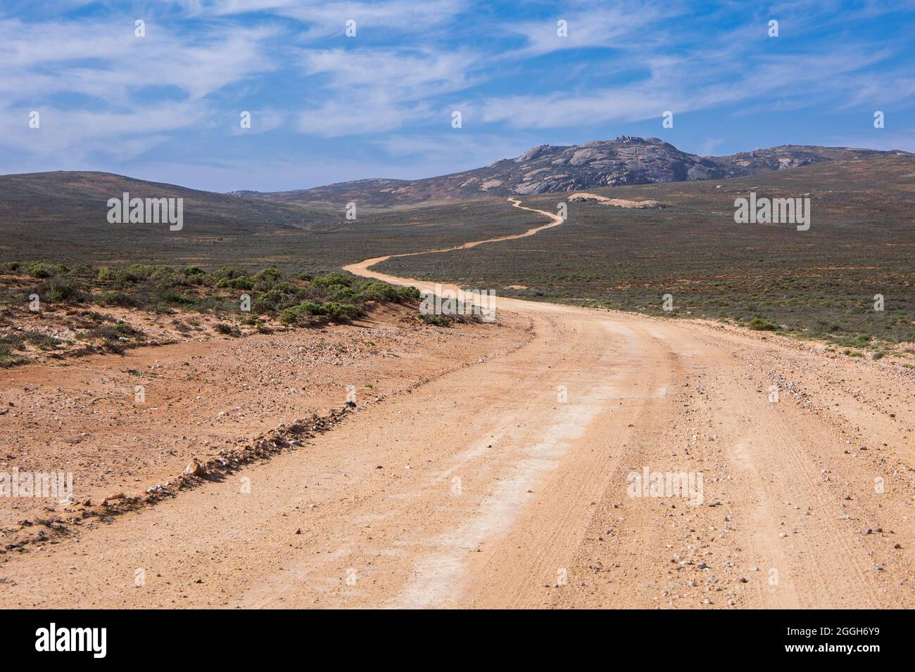 Une longue route de terre menant dans les montagnes au loin Banque D'Images