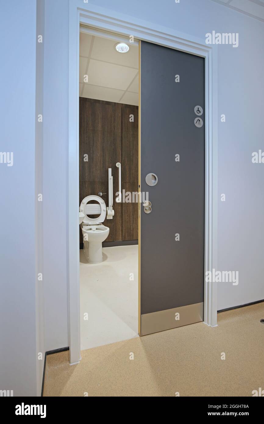 Une porte coulissante dissimulée donne accès à une toilette pour personnes handicapées dans un nouveau centre de santé de Londres Banque D'Images