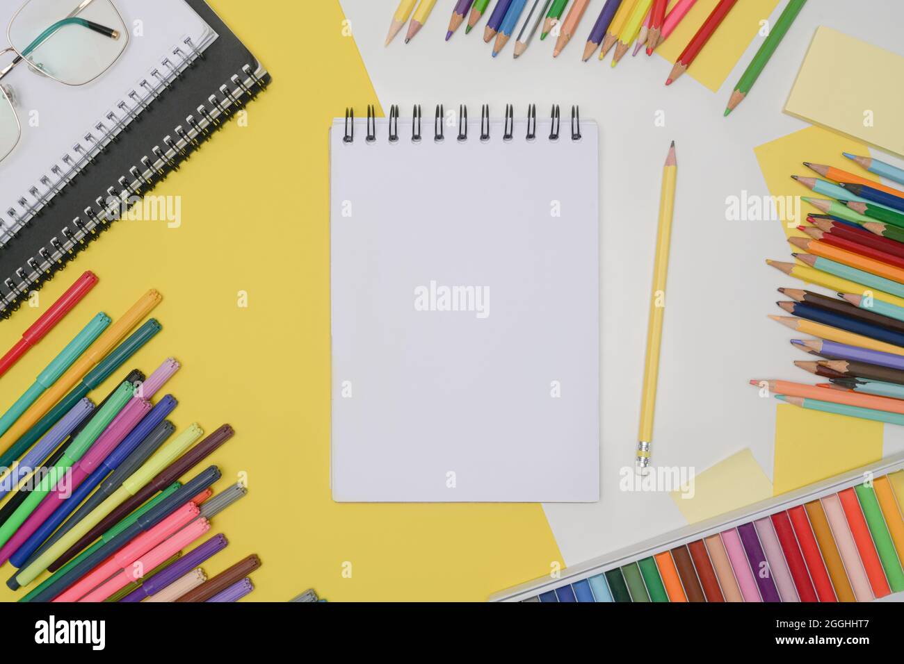 Carnet vide entouré de crayons de couleur. Concept de retour à l'école. Banque D'Images