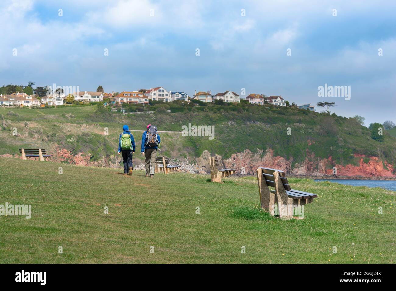 Couple marchant, vue arrière des personnes marchant sur le South West Coast Path, en direction de Broadsands Beach à Torbay, South Devon, Angleterre, Royaume-Uni Banque D'Images