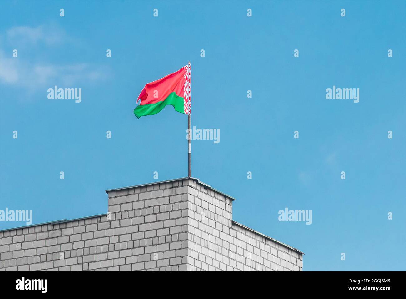 Drapeau bélarussien sur le bord d'un bâtiment en brique contre un ciel bleu. Banque D'Images
