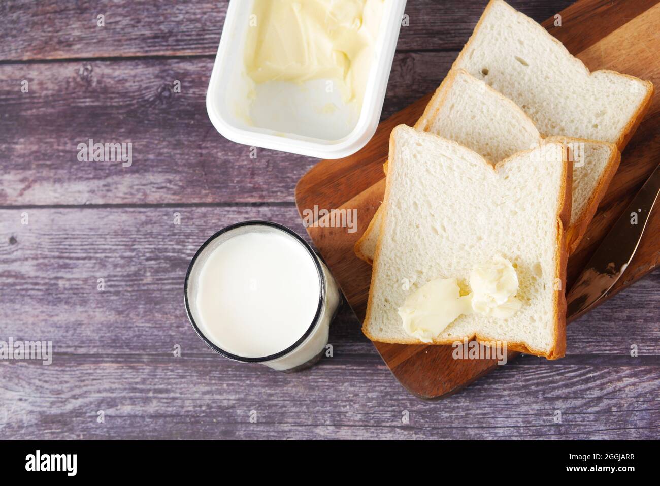du lait, du beurre et du pain sur une planche à découper sur une table Banque D'Images