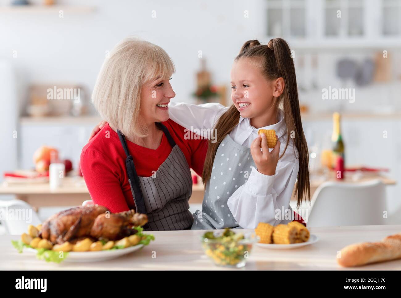 Cuisine familiale. Une grand-mère heureuse embrassant une jolie fille, faisant un traditionnel Thanksgiving ou un dîner de Noël dans la cuisine Banque D'Images